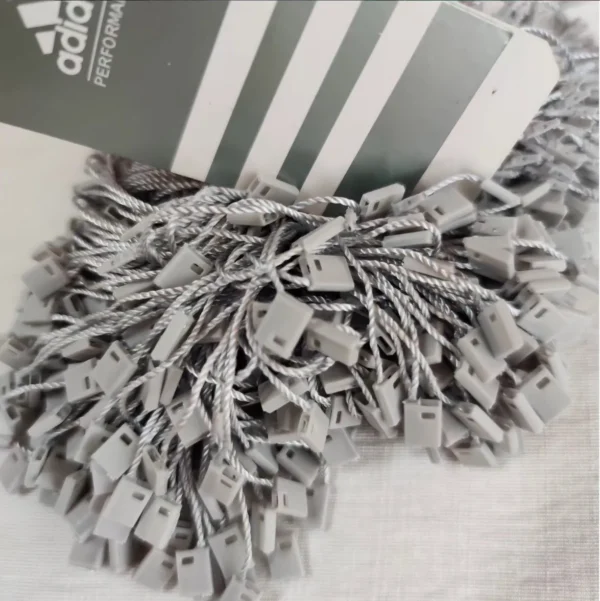 سفارش چاپ تگ مقوایی adidas به همراه نخ پلمپ طوسی تیراژ 1000 عددی