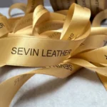 روبان طلایی 2/5 سانتی متری ساتن با چاپ مشکی SEVIN LEATHER متراژ 1000 متری